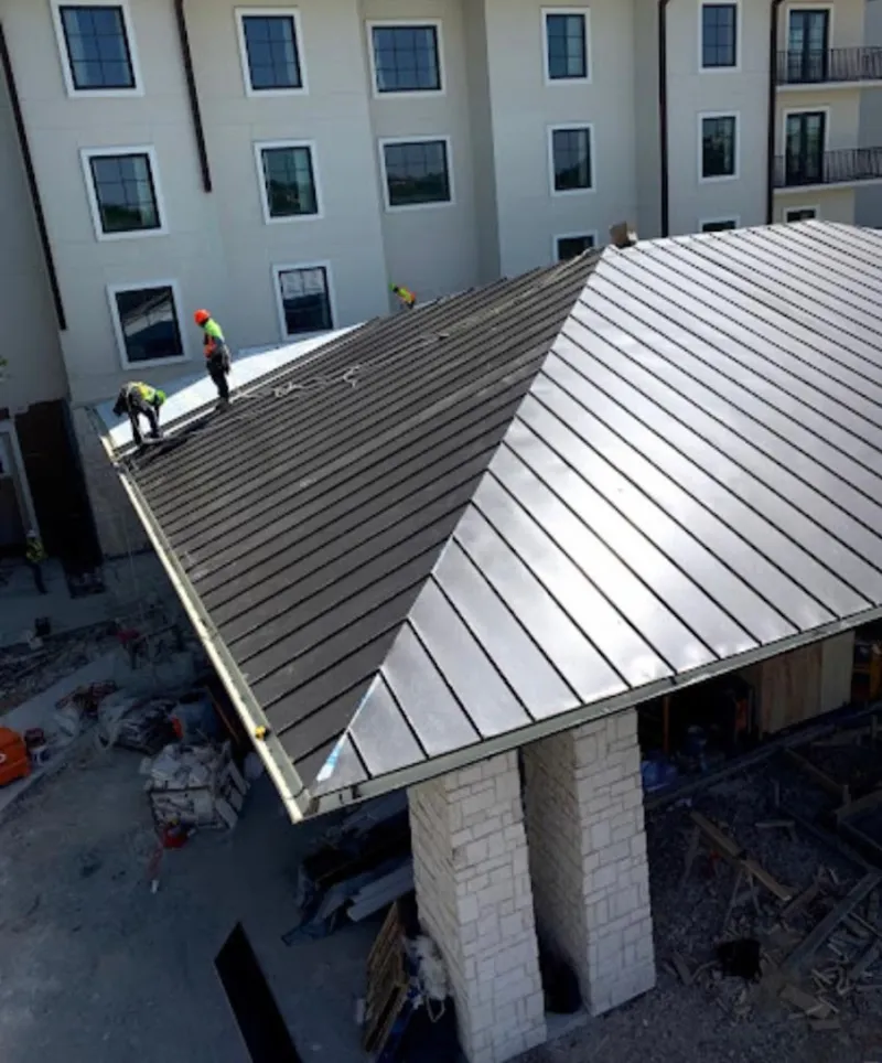 Crew installing standing seam metal roof panels on a commercial project in Hooper
